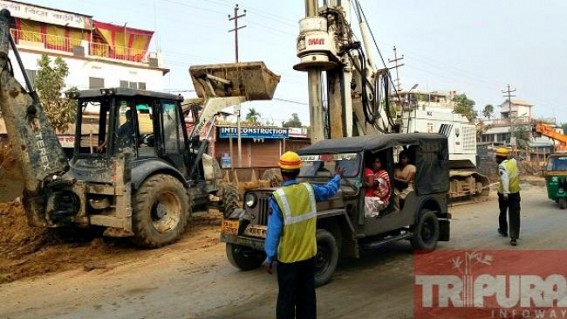 Construction workers managing traffic  : rain disrupts mud-filling work on NH-44 at Bordowali
